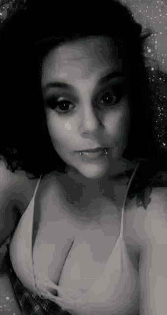 a woman is taking a selfie in a black and white photo while wearing a white tank top .