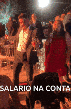 a man in a suit is dancing with a woman in a red dress and the words salario na conta are below him
