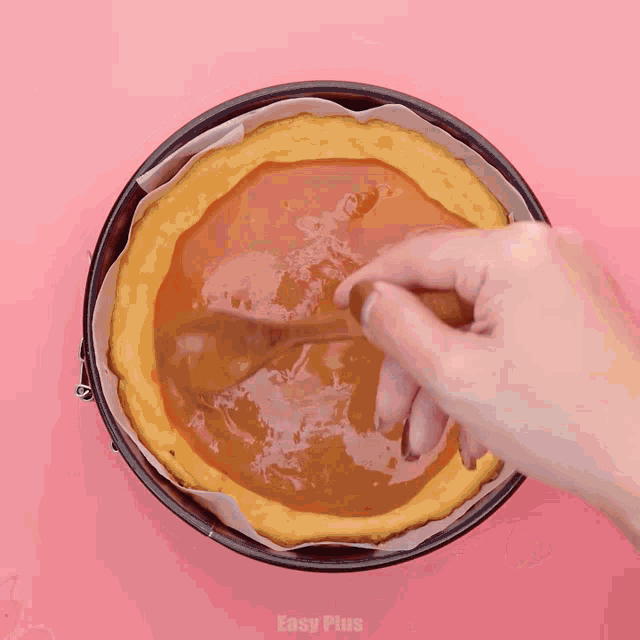 a person is spreading caramel on a pie with a wooden spoon ..