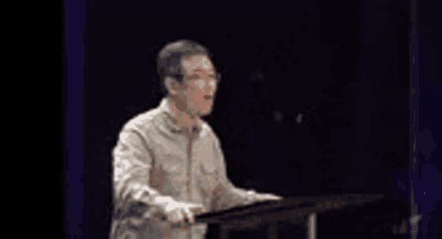 a man is standing at a podium giving a speech in front of a microphone .