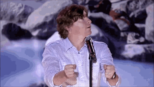 a man stands in front of a microphone with his hands outstretched