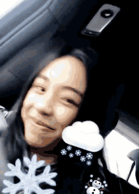 a girl in a car is holding a snowflake and a cloud