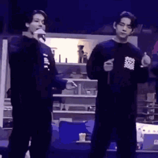 a couple of men are standing next to each other on a stage .