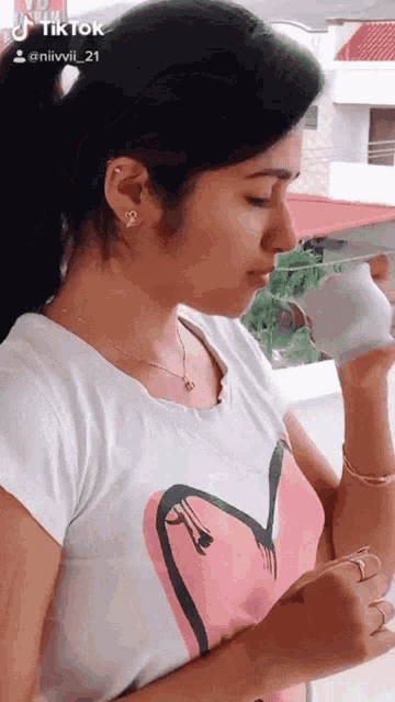 a woman wearing a pink flamingo shirt drinks from a cup