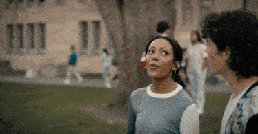 a man and a woman are standing next to each other in a park