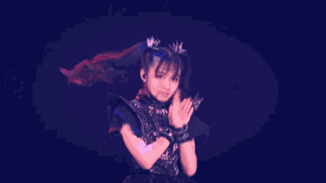 a woman in a black dress is dancing in front of a blue background