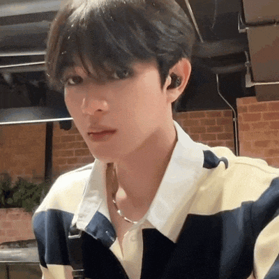 a young man wearing a striped shirt and a necklace .