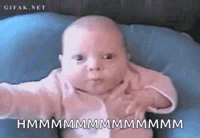 a baby is making a funny face while laying on a blue pillow .