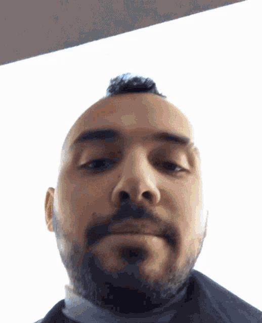 a bald man with a beard is looking at the camera