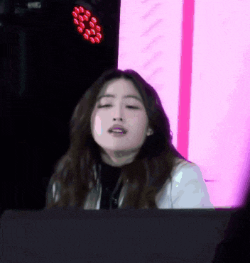 a woman is sitting in front of a pink light and making a face