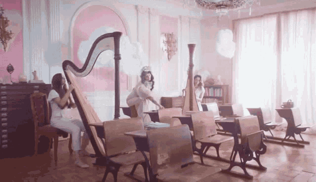 a group of girls are playing harps in a room
