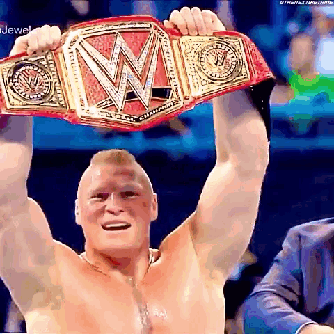 a man is holding a wrestling championship belt above his head .