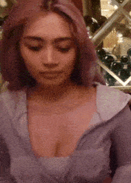 a woman with purple hair is wearing a purple shirt with a plunging neckline .