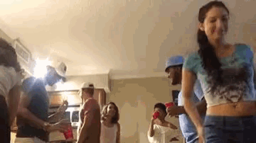 a group of people are dancing in a living room with red cups .