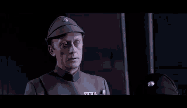 a man in a military uniform is standing in a dark room and looking at something .