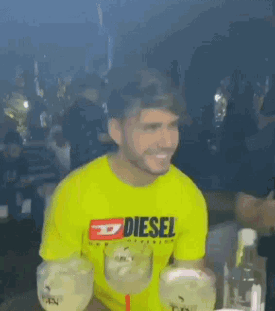 a man wearing a yellow diesel t-shirt is holding two glasses