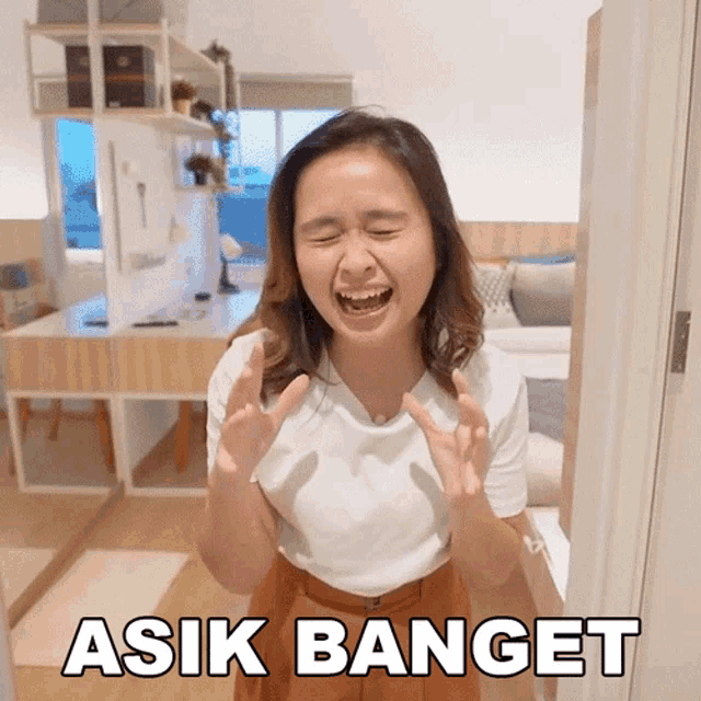 a woman in a white shirt is screaming with asik banget written on the bottom