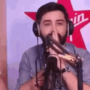 a man with a beard is singing into a microphone while wearing headphones and a watch .