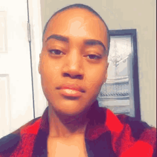 a woman wearing a red and black plaid shirt looks at the camera
