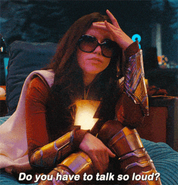 a woman in a superhero costume is sitting on a bed and asking do you have to talk so loud