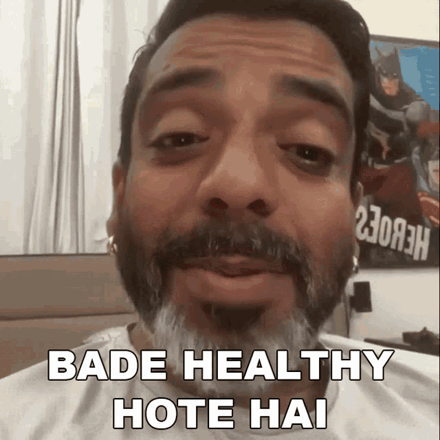 a man with a beard says bade healthy hote hai in front of a batman poster