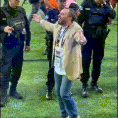 a man in a tan jacket has a lanyard around his neck that says ' u.s.a. '