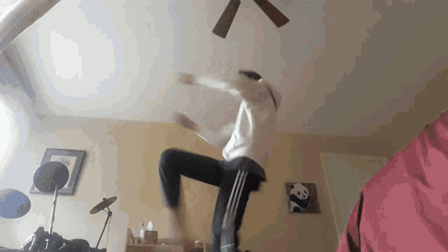a person is jumping in the air in front of a drum set and a ceiling fan