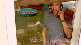 a man is talking on a cell phone behind a window