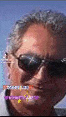 a close up of a man wearing sunglasses with the words " sadullah " on the bottom right