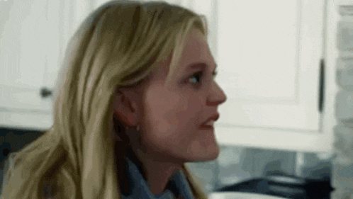 a woman is sitting in a kitchen looking at something .