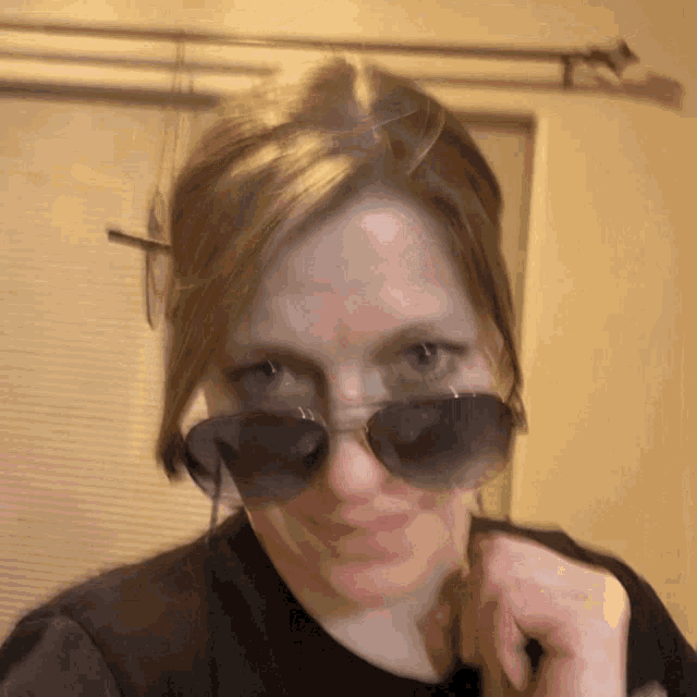 a woman wearing sunglasses and a black shirt is looking at the camera