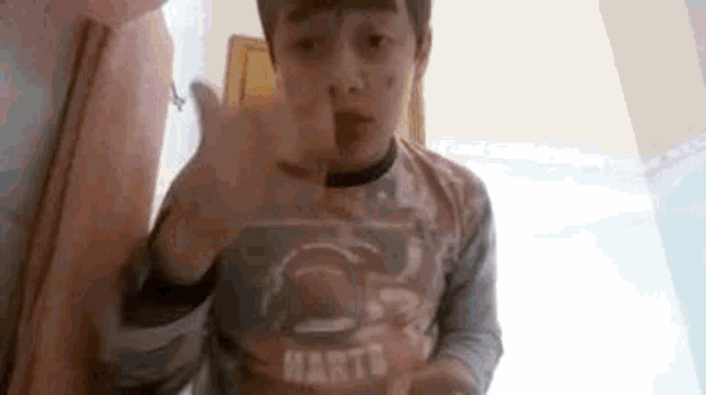 a young boy is giving a thumbs up sign while wearing a shirt that says `` mart '' .