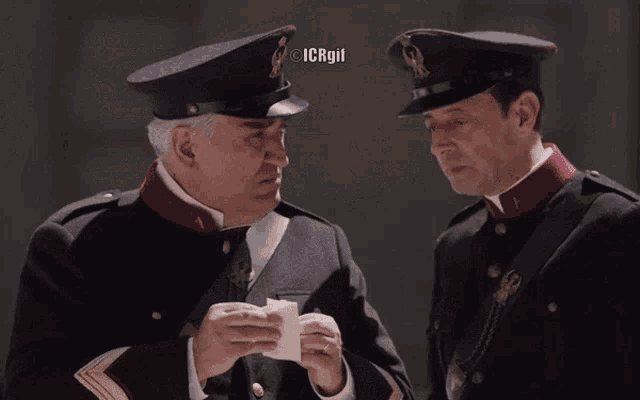 two men in military uniforms are standing next to each other with icrgil written on the bottom