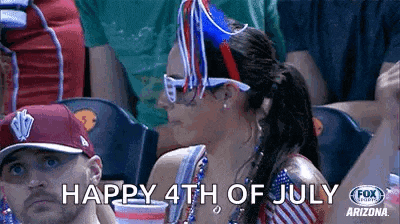 a woman wearing a hat and sunglasses is sitting in a crowd of people and says happy 4th of july