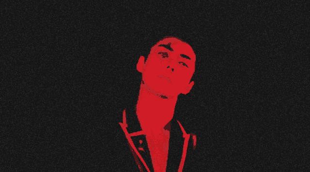 a close up of a man 's face with a red light behind him