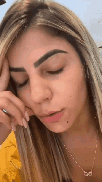 a woman with blonde hair and a necklace with an infinity symbol on it