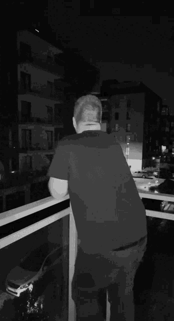 a man in a black shirt is standing on a balcony