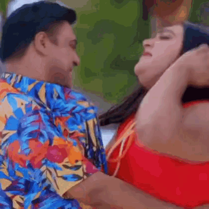 a man and woman are kissing and the woman is wearing a red top