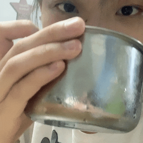 a close up of a person holding a metal cup