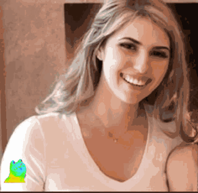 a woman is smiling and wearing a white shirt with a frog on her sleeve .