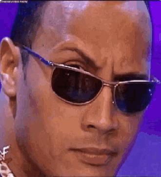 a close up of a man wearing sunglasses and a necklace