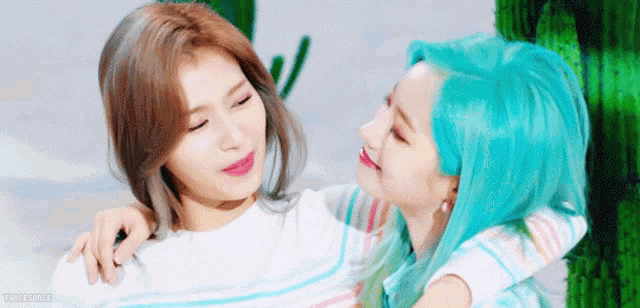 two women with blue hair are hugging each other and smiling .
