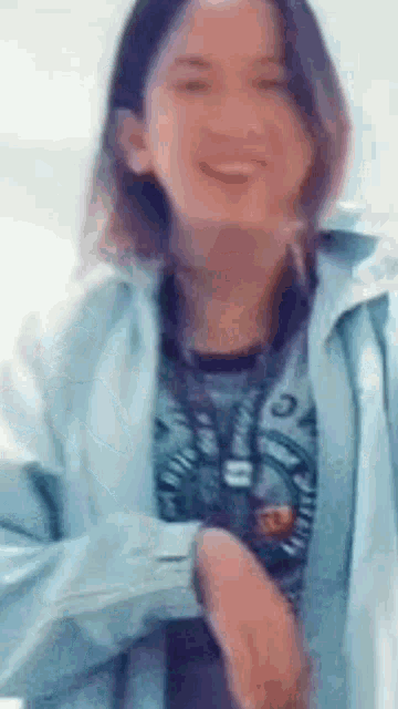 a woman wearing a blue jacket and a black shirt is smiling and dancing .