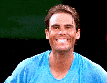 a man wearing a blue shirt is smiling with his mouth open