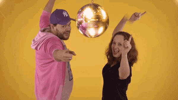 a man in a ny hat holds a disco ball over a woman