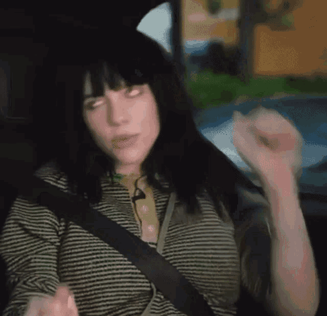 a woman is sitting in the back seat of a car with her eyes closed and a seat belt .
