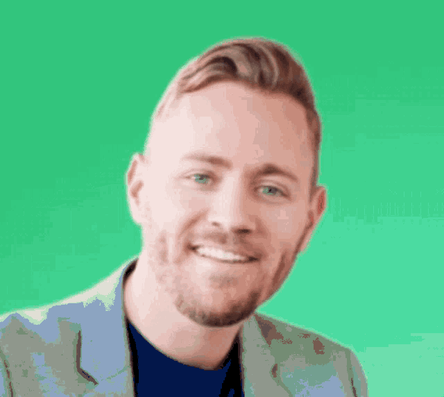 a man with a beard and blue eyes is smiling in front of a green background .