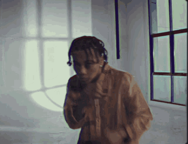 a man with dreadlocks is standing in a room with a window