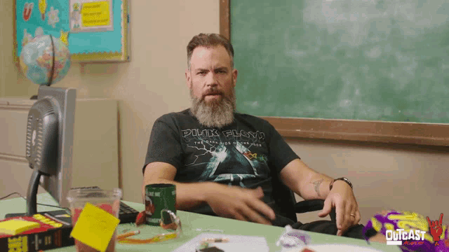 a man in a pink floyd shirt sits at a desk