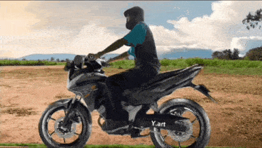 a man is riding a motorcycle on a dirt road with y.art written on the side